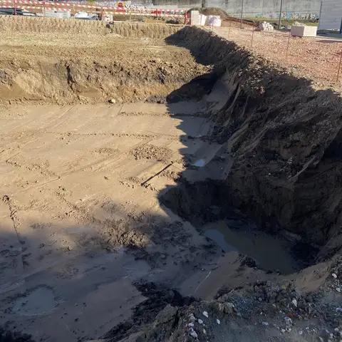 Sloped excavation wall with a sandy floor.