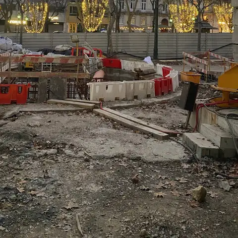 Construction materials and barriers staged on an urban site at dusk.
