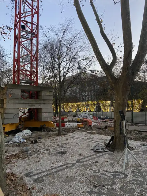Tower crane base and patterned paving on a city site at dusk.