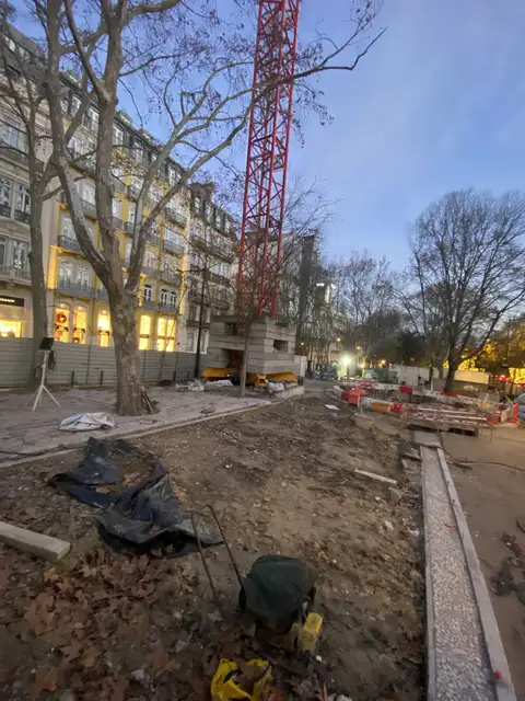 Street-side construction works with a crane at dusk.